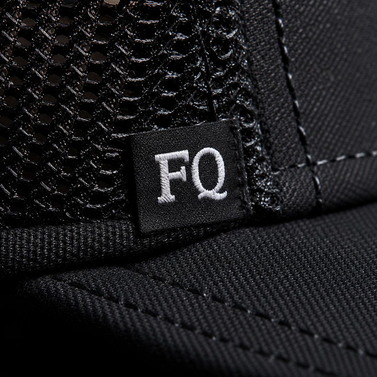 Närbild på broderad FQ-logotyp på en FORQUE-keps